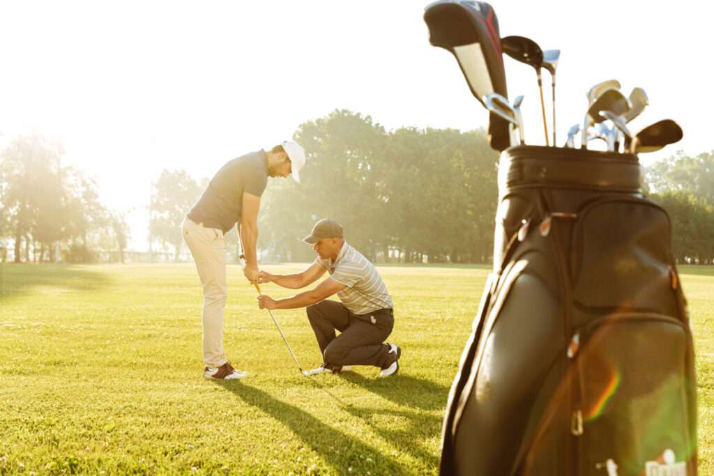 Personal trainer giving a lesson to a young male golfer